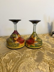 A pair of hand-painted glass margarita glasses with floral and leaf motifs.