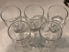 A set of five clear glass vintage cordial or small wine glasses.