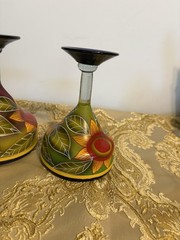 A pair of hand-painted glass margarita glasses with floral and leaf motifs.