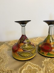 A pair of hand-painted glass margarita glasses with floral and leaf motifs.